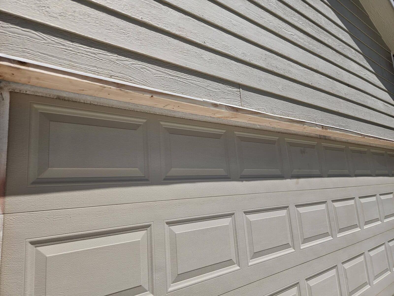 New white garage door with grey vinyl siding